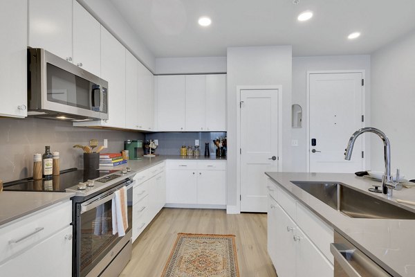 Modern kitchen with stainless steel appliances and granite countertops at The Dorsey Apartments, luxury Greystar community