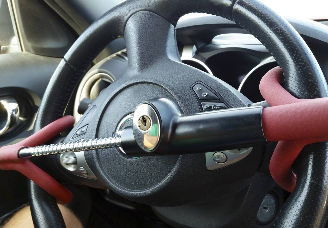 A close-up view of a steering wheel locked with a red and black security device.
