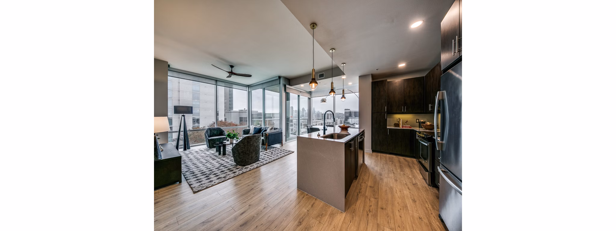 Open-concept living area with sleek hardwood floors and modern kitchen at 3700M Apartments
