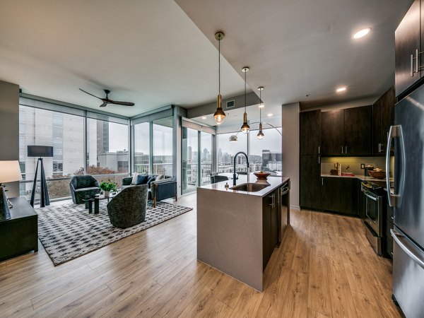 Open-concept living area with sleek hardwood floors and modern kitchen at 3700M Apartments
