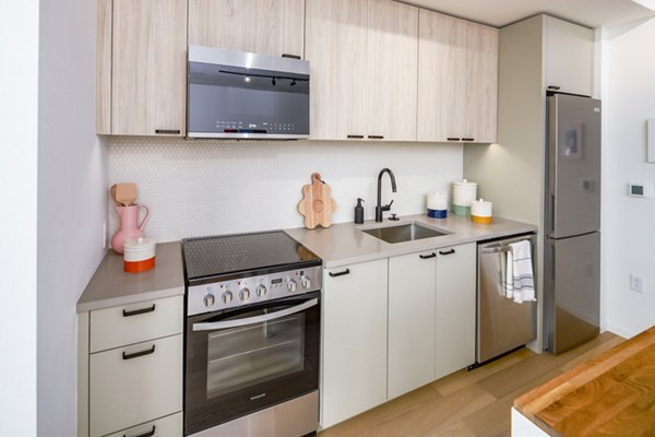 Modern kitchen with stainless steel appliances and granite countertops in 1111 Church Apartments