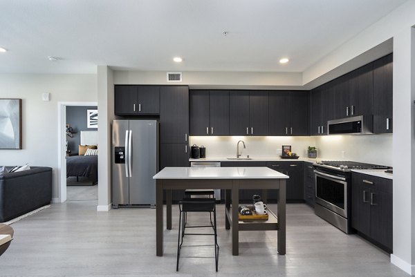 Modern kitchen with stainless steel appliances and marble countertops at Prado Apartments