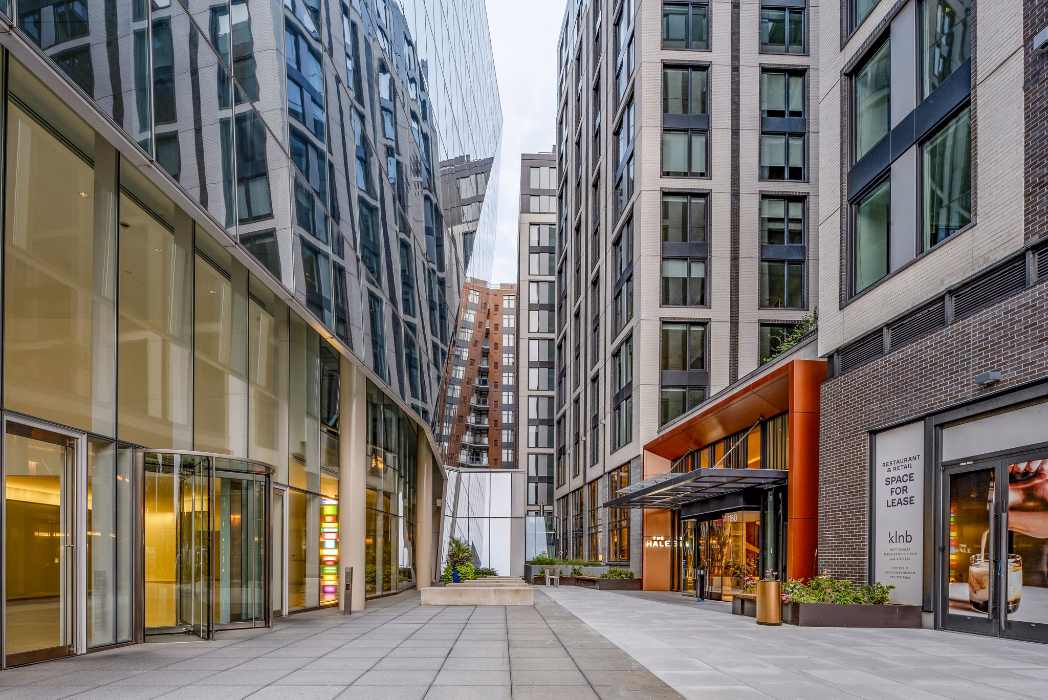 Modern urban complex with glass and brick facades featuring a walkway at luxury apartments