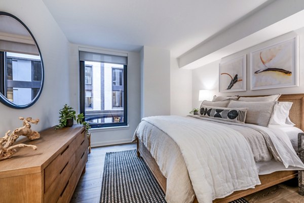 Modern bedroom featuring a comfortable bed, stylish dresser, and vibrant wall art with natural light from the window