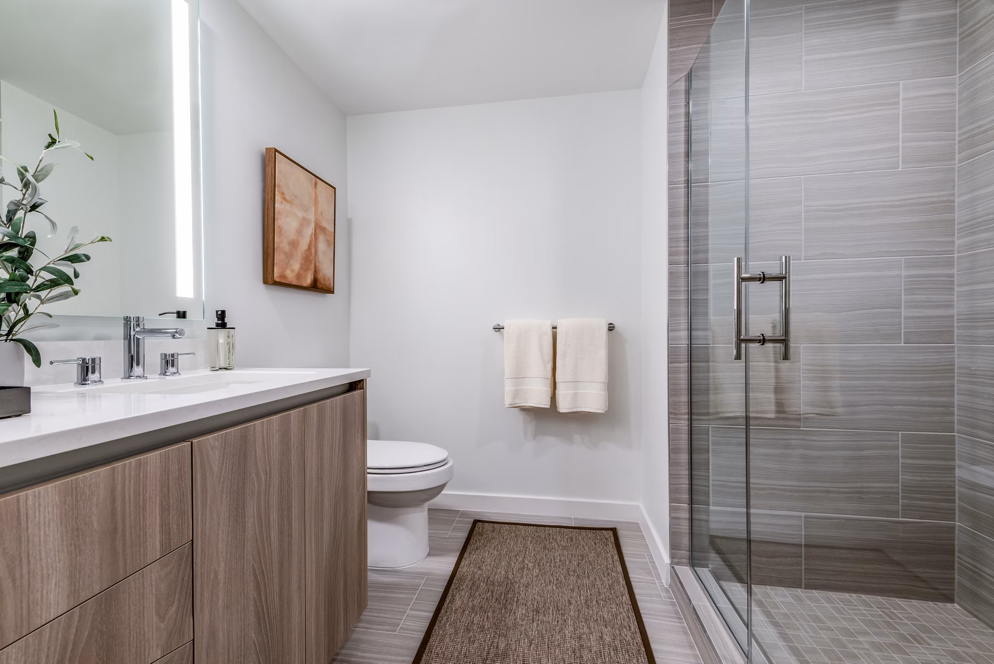 Modern bathroom with glass shower and elegant vanity in luxury apartment Features towels and small plant for a stylish touch