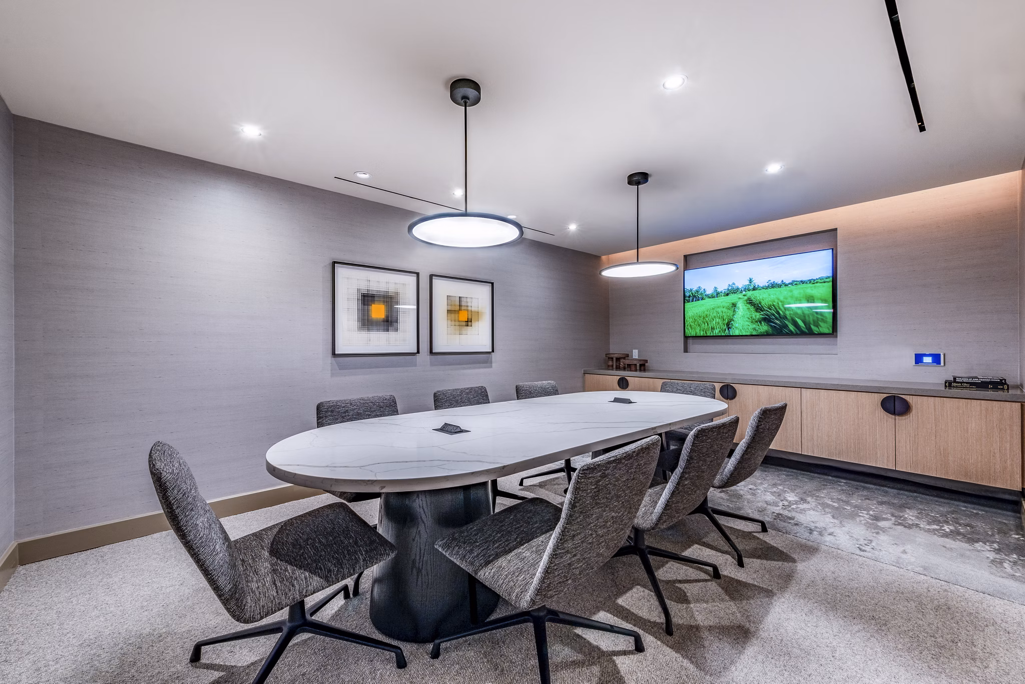 Modern conference room featuring a long table, comfortable chairs, and a large screen for presentations