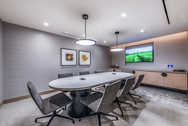 Modern conference room featuring a long table, comfortable chairs, and a large screen for presentations