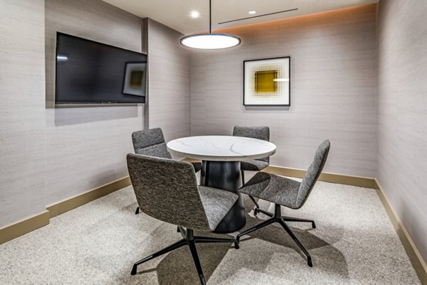 Small meeting room featuring a round table, four chairs, and a wall-mounted TV