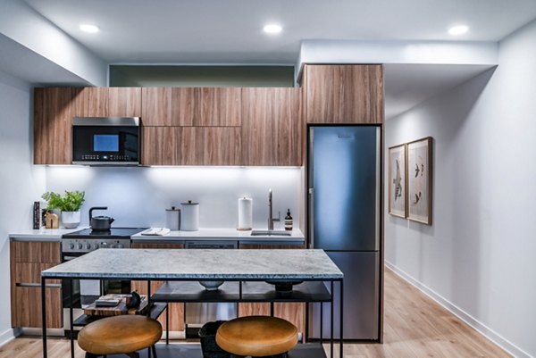 Modern kitchen with wooden cabinets, appliances, and an island with stools in luxury apartments