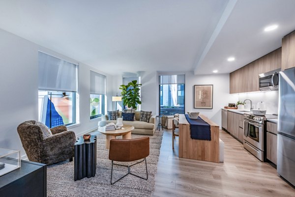 Modern open-concept living room and kitchen with stainless steel appliances and large windows in luxury apartment