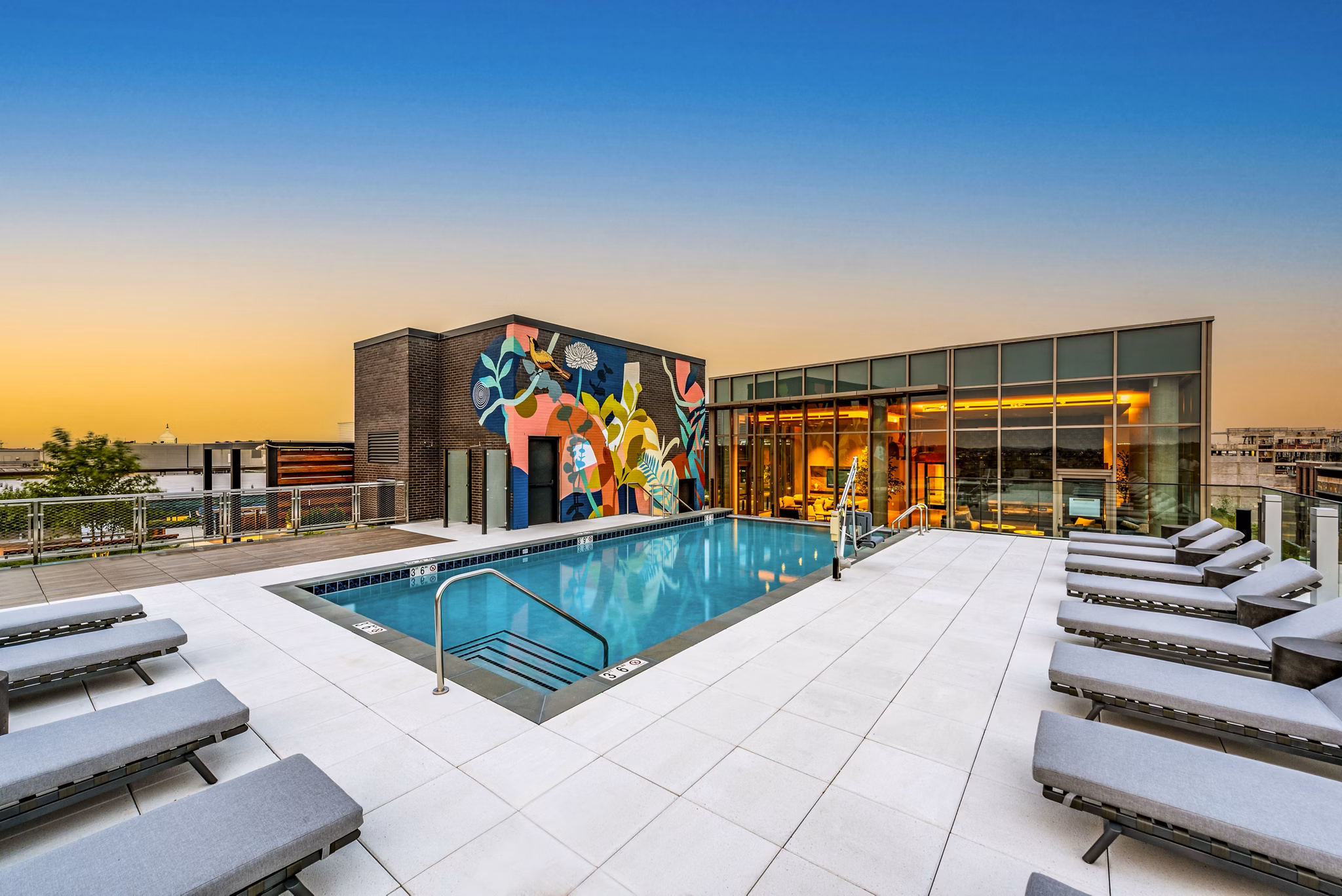 Rooftop pool area with lounge chairs and vibrant mural in luxury apartments
