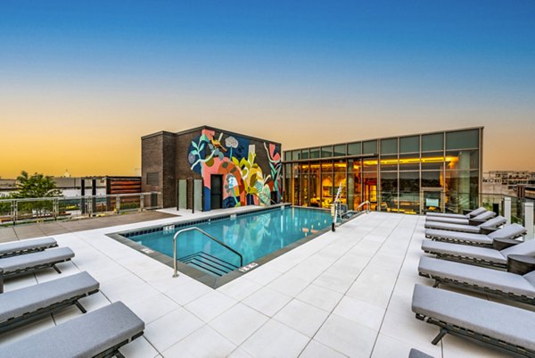 Rooftop pool area with lounge chairs and vibrant mural in luxury apartments