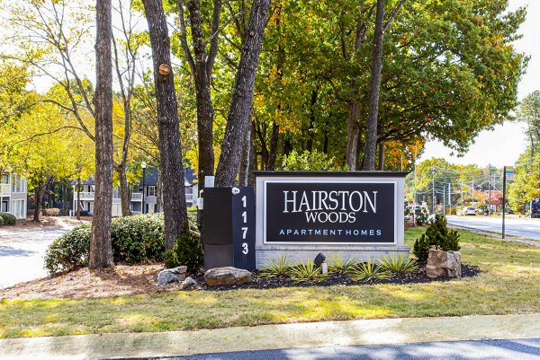 Hairston Woods Apartments: Signage at elegant luxury apartment entrance in lush community setting