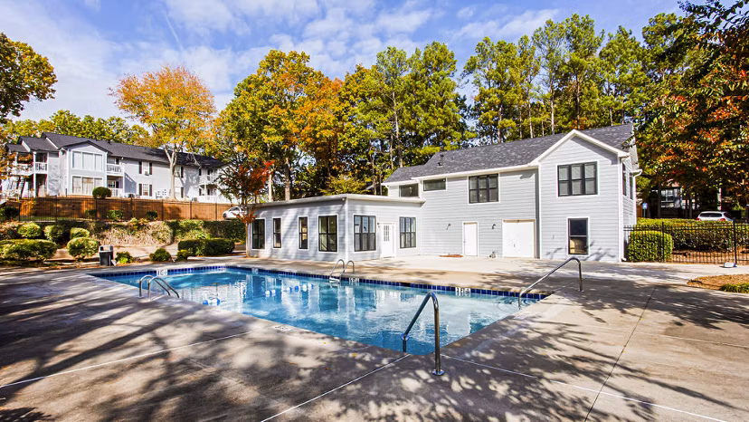 Resort-style pool surrounded by lush greenery at Hairston Woods Apartments