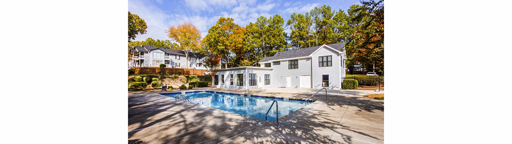 Resort-style pool surrounded by lush greenery at Hairston Woods Apartments