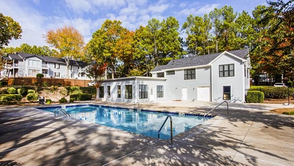 Resort-style pool surrounded by lush greenery at Hairston Woods Apartments
