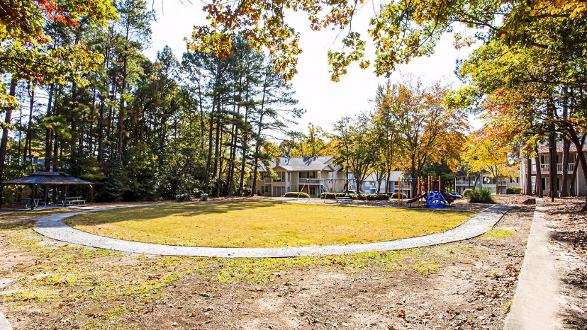 Playground with modern equipment at Hairston Woods Apartments, perfect for family fun and outdoor activity enjoyment