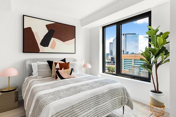 Spacious bedroom with modern decor at The Metlo Apartments featuring elegant bedding and ample natural light