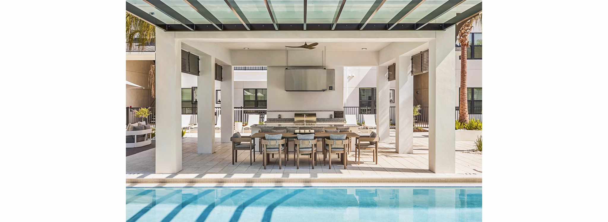 Outdoor grill area and patio next to a pool, with modern seating at Asbury Apartments