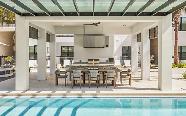 Outdoor grill area and patio next to a pool, with modern seating at Asbury Apartments