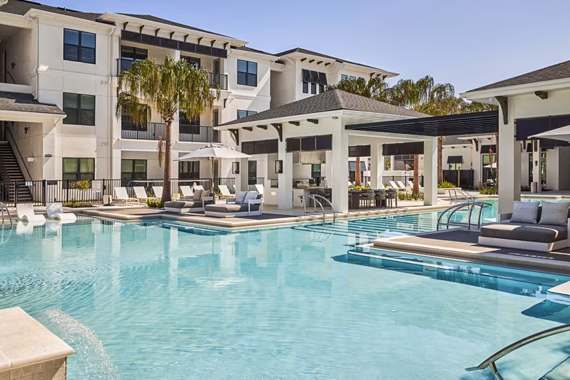 Inviting poolside relaxation area at Asbury Apartments, featuring modern outdoor seating and lush greenery