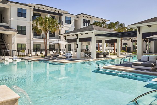 Inviting poolside relaxation area at Asbury Apartments, featuring modern outdoor seating and lush greenery