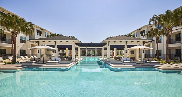 Luxurious pool at Asbury Apartments featuring sleek lounge chairs and lush greenery Perfect for relaxation and social gatherings