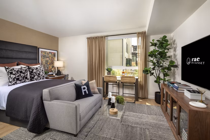 Modern bedroom with elegant decor and ample natural light at Rae on Sunset Apartments