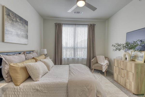 Cozy bedroom with modern decor at Tacara Gruene Apartments, featuring plush bedding and ample natural light in luxury community settings