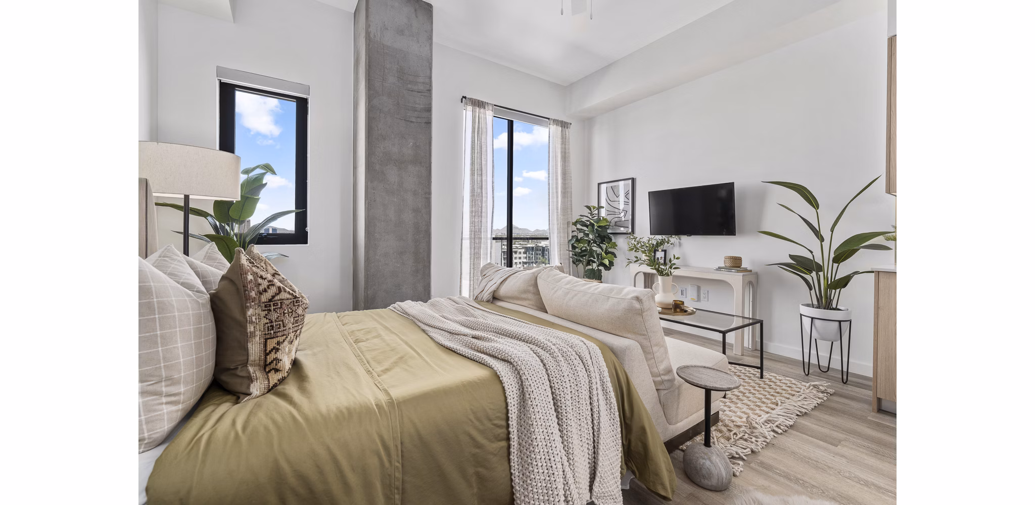 Cozy bedroom with modern decor and large windows at Moontower PHX Apartments