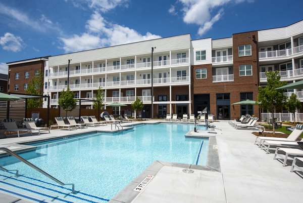 Modern outdoor pool at The Whitby featuring poolside lounge chairs and greenery, offering a luxury relaxation experience