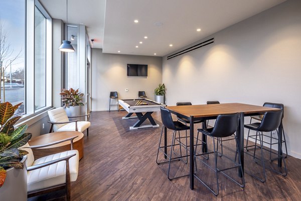 Modern game room with pool table, high-top seating, and large windows at luxury apartments