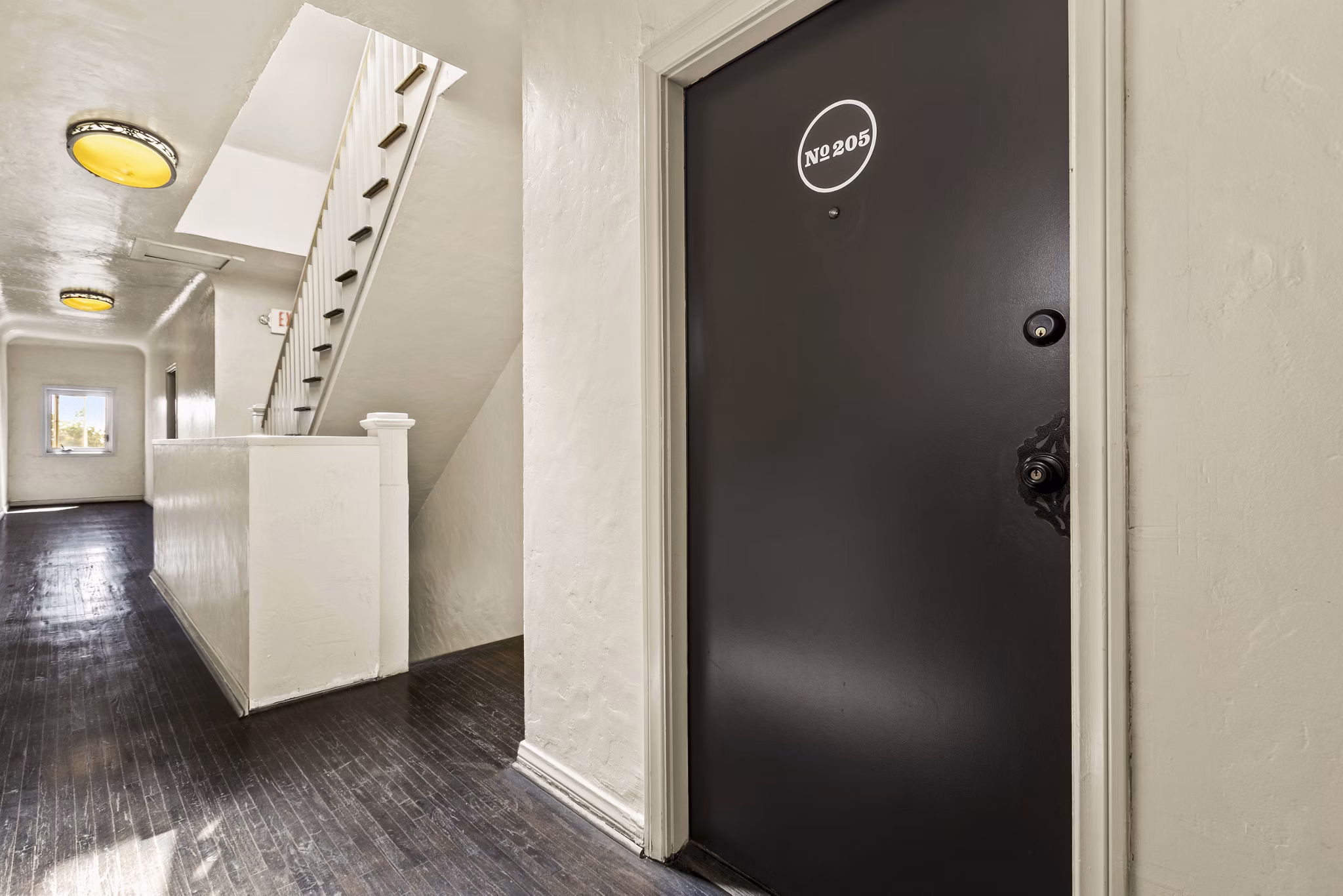 Elegant hallway with wooden staircase and resident entry at Delta Apartments
