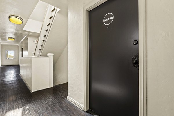 Elegant hallway with wooden staircase and resident entry at Delta Apartments