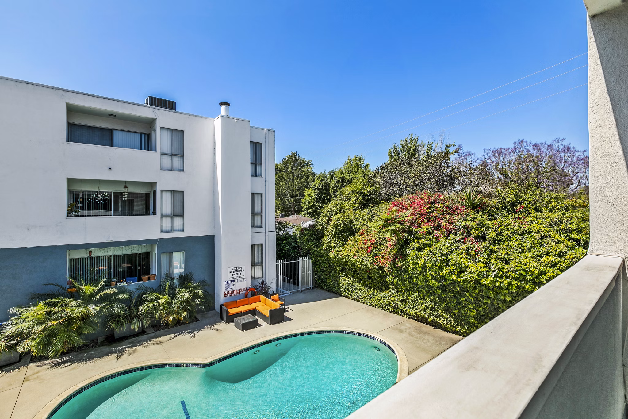 Patio/balcony view overlooking modern pool at The Fulton Apartments, offering luxurious outdoor living spaces