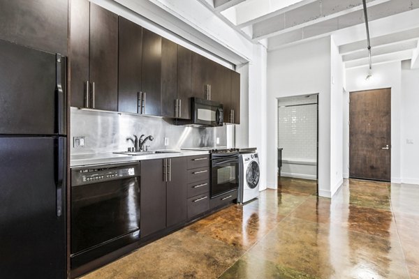 Modern kitchen with stainless steel appliances and island counter at South Park Lofts Apartments, luxury living in an urban setting