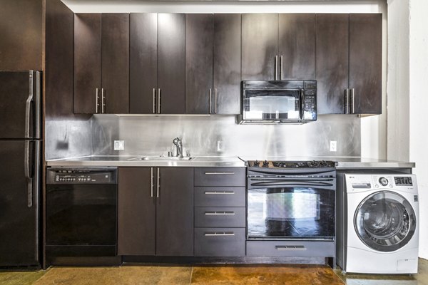 Modern kitchen featuring stainless steel appliances and sleek cabinetry in South Park Lofts Apartments