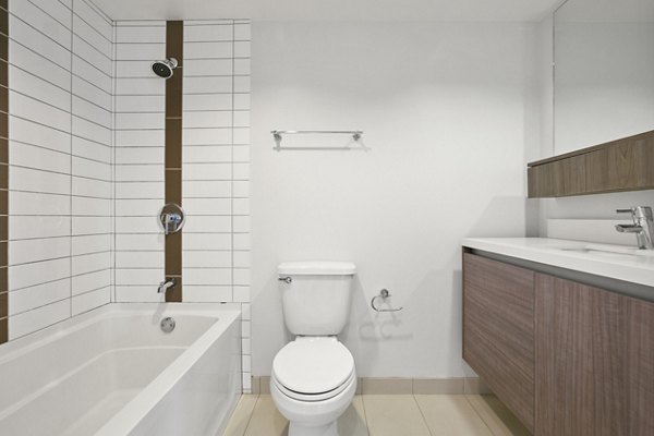 Minimalist bathroom with bathtub, toilet, and wooden vanity at The View Apartments