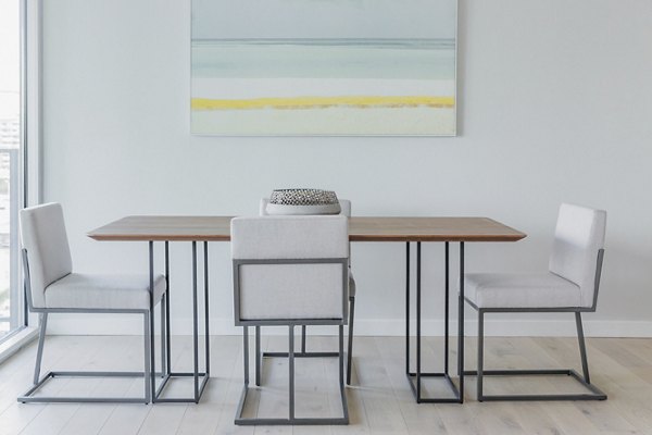 The View Apartments: Minimalist dining area with table, four chairs, and beach painting