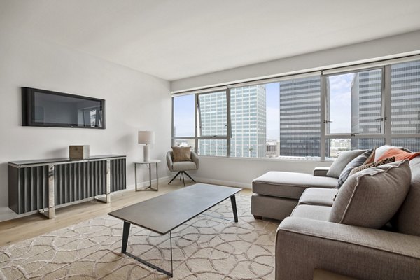 Spacious living room with large windows, sofa, and TV at The View Apartments