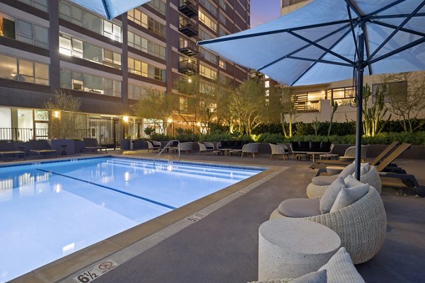 The View Apartments: Outdoor pool area with lounge chairs and umbrellas at dusk, luxurious setting in this high-end apartment community