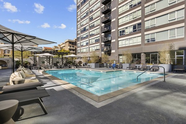 Outdoor pool area with lounge chairs and umbrellas by a building at The View Apartments