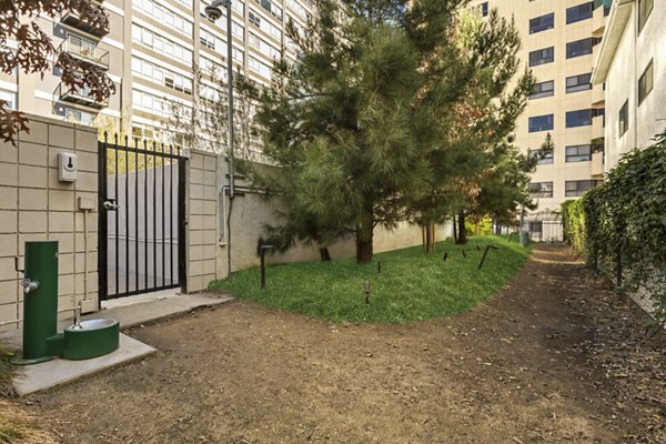 Gated outdoor area with trees, grass, and a water fountain at The View Apartments