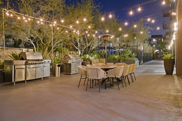 Outdoor patio with string lights, grills, and dining table at The View Apartments