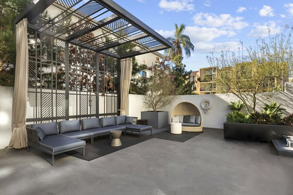 Outdoor patio with modern furniture and pergola, surrounded by greenery at The View Apartments