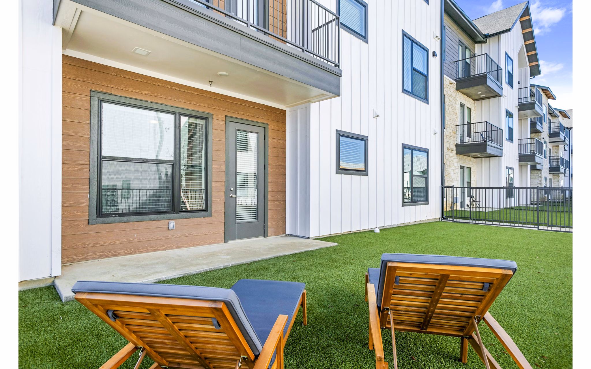 Backyard patio with stylish seating and lush greenery at The Gin Mill Apartments, perfect for outdoor relaxation and social gatherings
