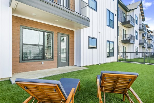 Backyard patio with stylish seating and lush greenery at The Gin Mill Apartments, perfect for outdoor relaxation and social gatherings
