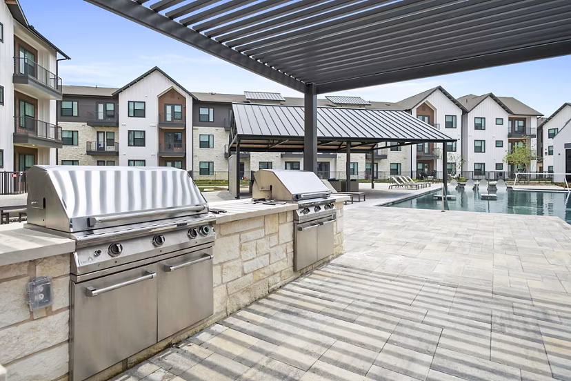 Outdoor grill area on a spacious patio at The Gin Mill Apartments, offering a perfect setting for social gatherings and relaxation