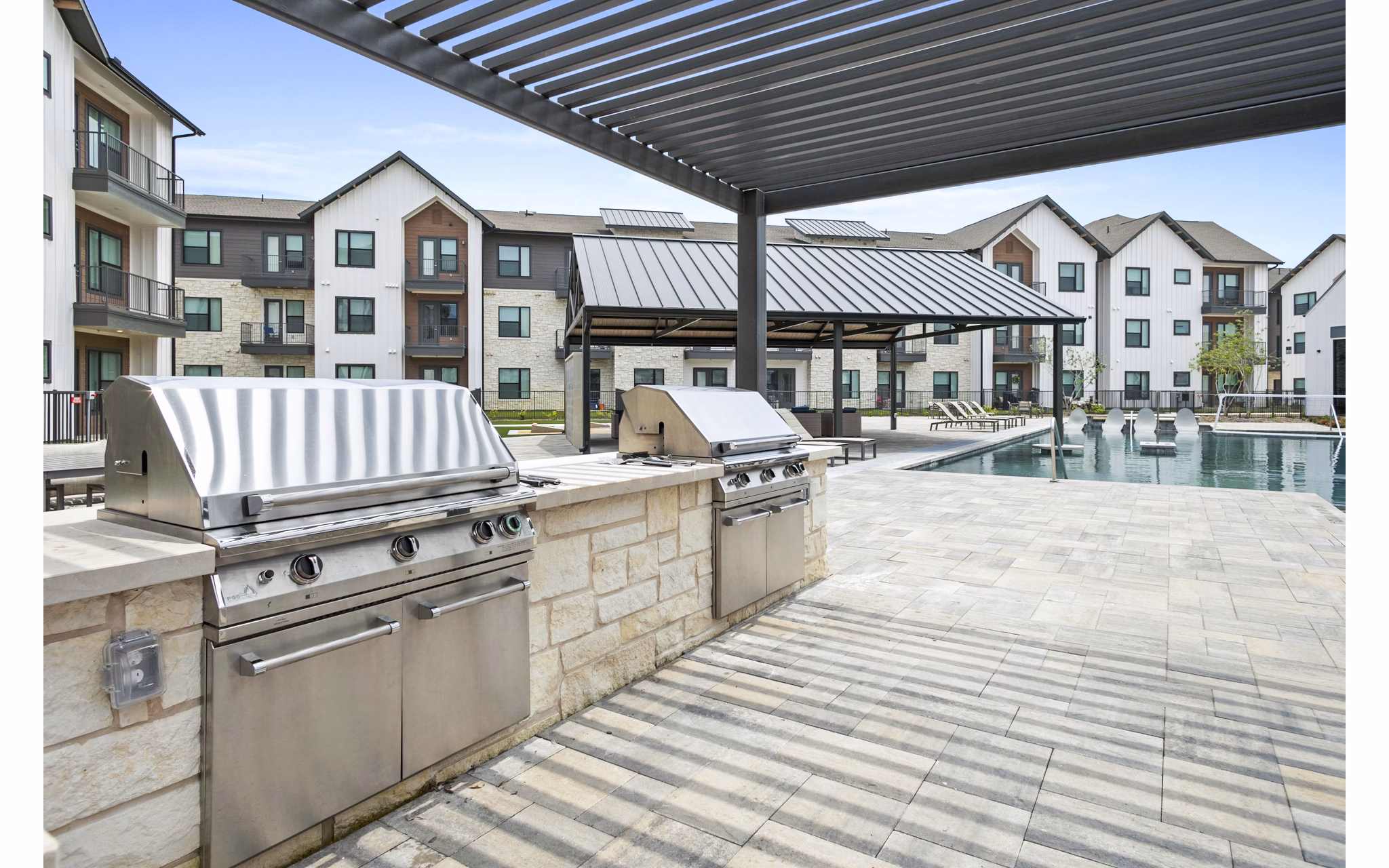 Outdoor grill area on a spacious patio at The Gin Mill Apartments, offering a perfect setting for social gatherings and relaxation