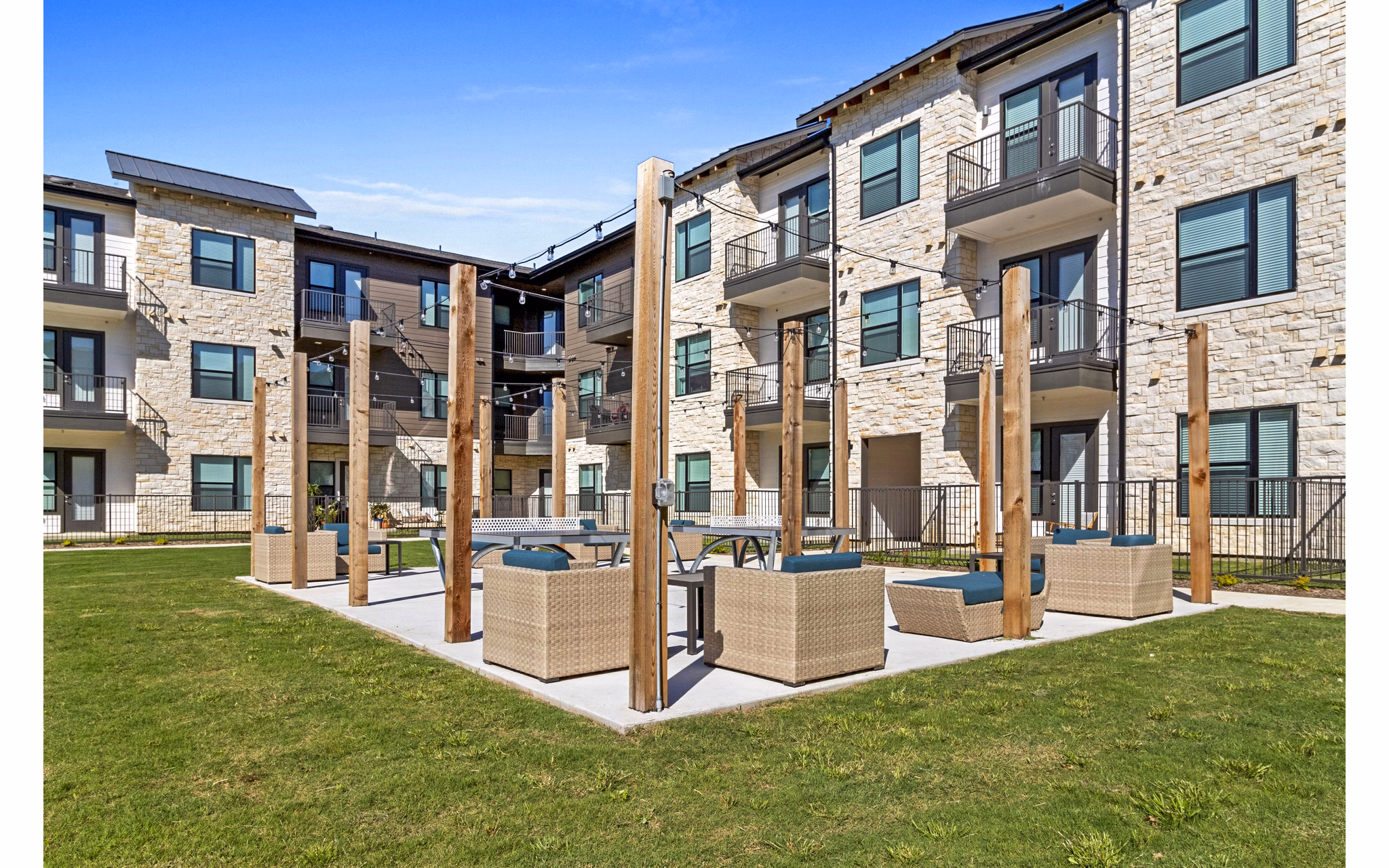Outdoor recreational patio with seating and string lights at The Gin Mill Apartments, ideal for relaxation and entertainment